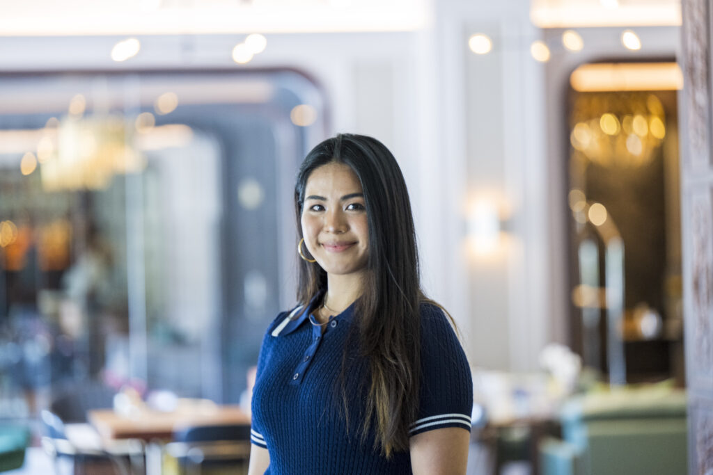 Young international hospitality trainee smiling confidently at a luxury hotel, representing global opportunities and career growth