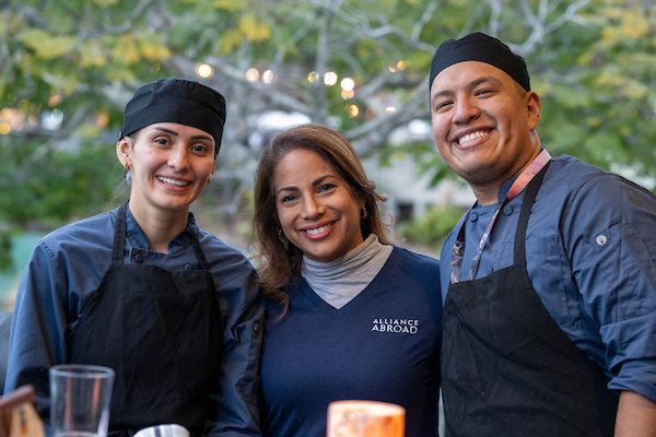 Two young chefs and a program mentor from Alliance Abroad smiling together, showcasing culinary skills and international training experience.
