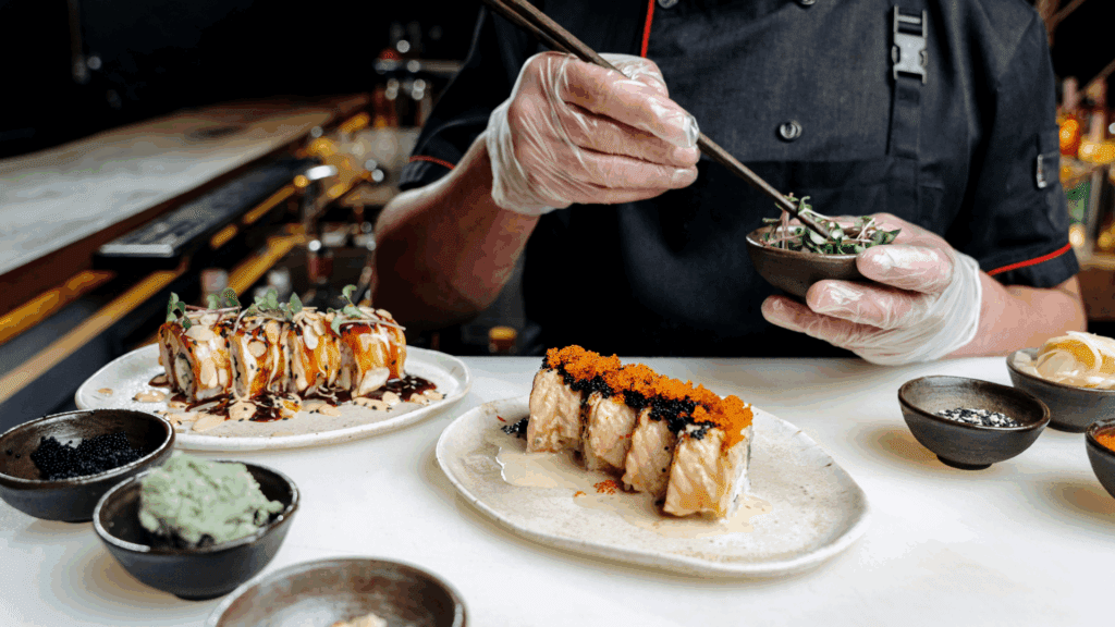 Chef carefully plating sushi rolls in a professional kitchen, showcasing advanced culinary skills and precise cooking techniques.